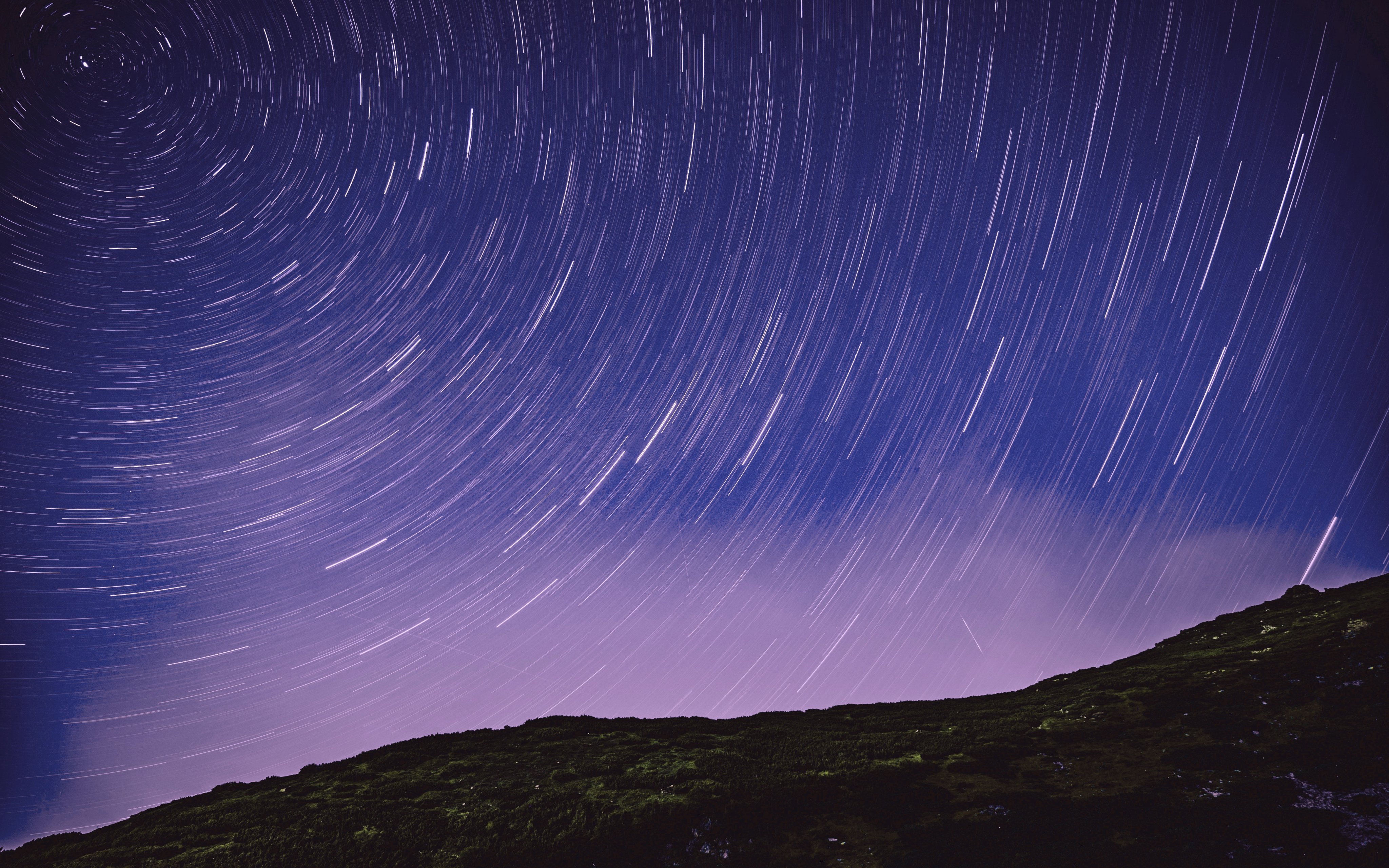 Long exposure stars over a mountain ridge.