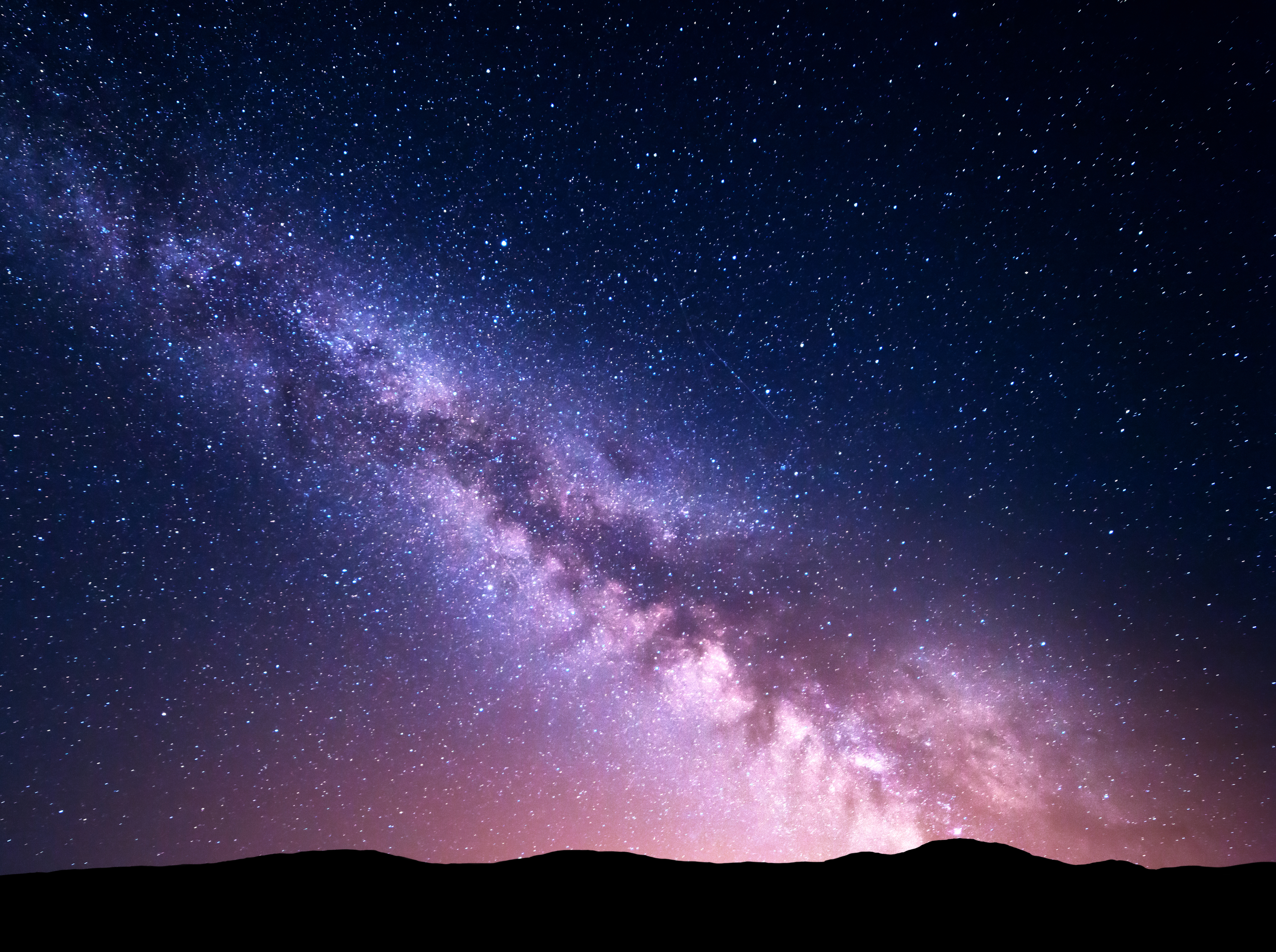 A starry night sky above a silhouetted mountain landscape.