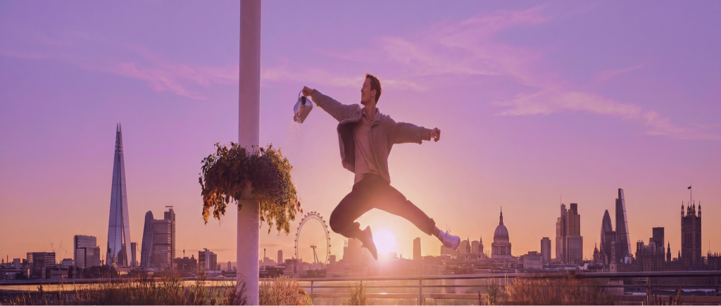 A person jumping in front of the London skyline at sunset.